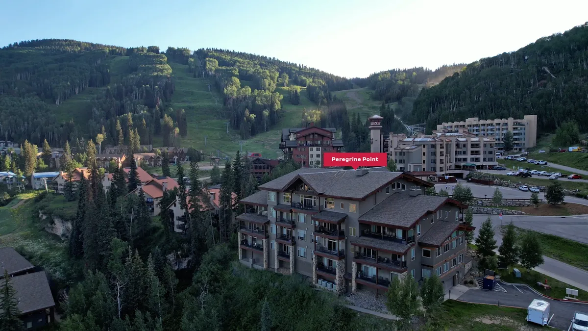 This image highlights the Peregrine Point building nestled amidst trees with a stunning mountain backdrop. The scene captures the easy access families have to the resort and the beautiful natural surroundings that set the stage for adventure and relaxation.